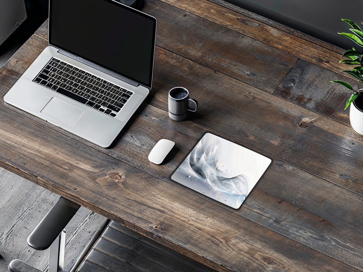 Mouse pad on a dark wood desk with a laptop, coffee mug, and plant, for a cozy work environment.