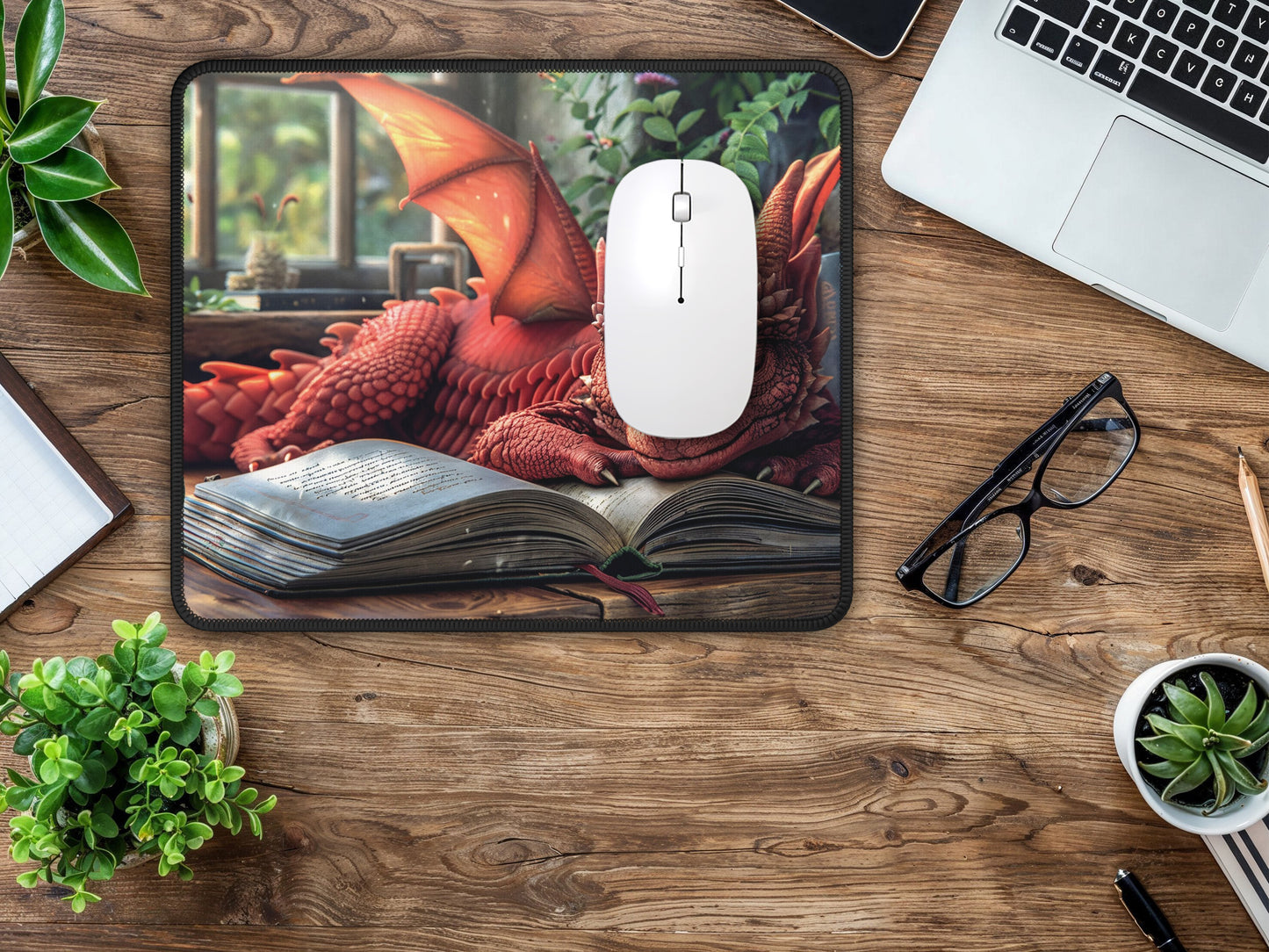 A small mouse pad with a vibrant red dragon atop a book enhances a minimalist desk setup, offering an escape into a fantastical world.