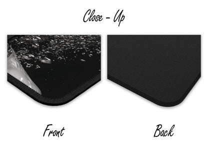 Close-up detail of mouse pad showing the textured front with a water-themed image and the smooth black rubber back.