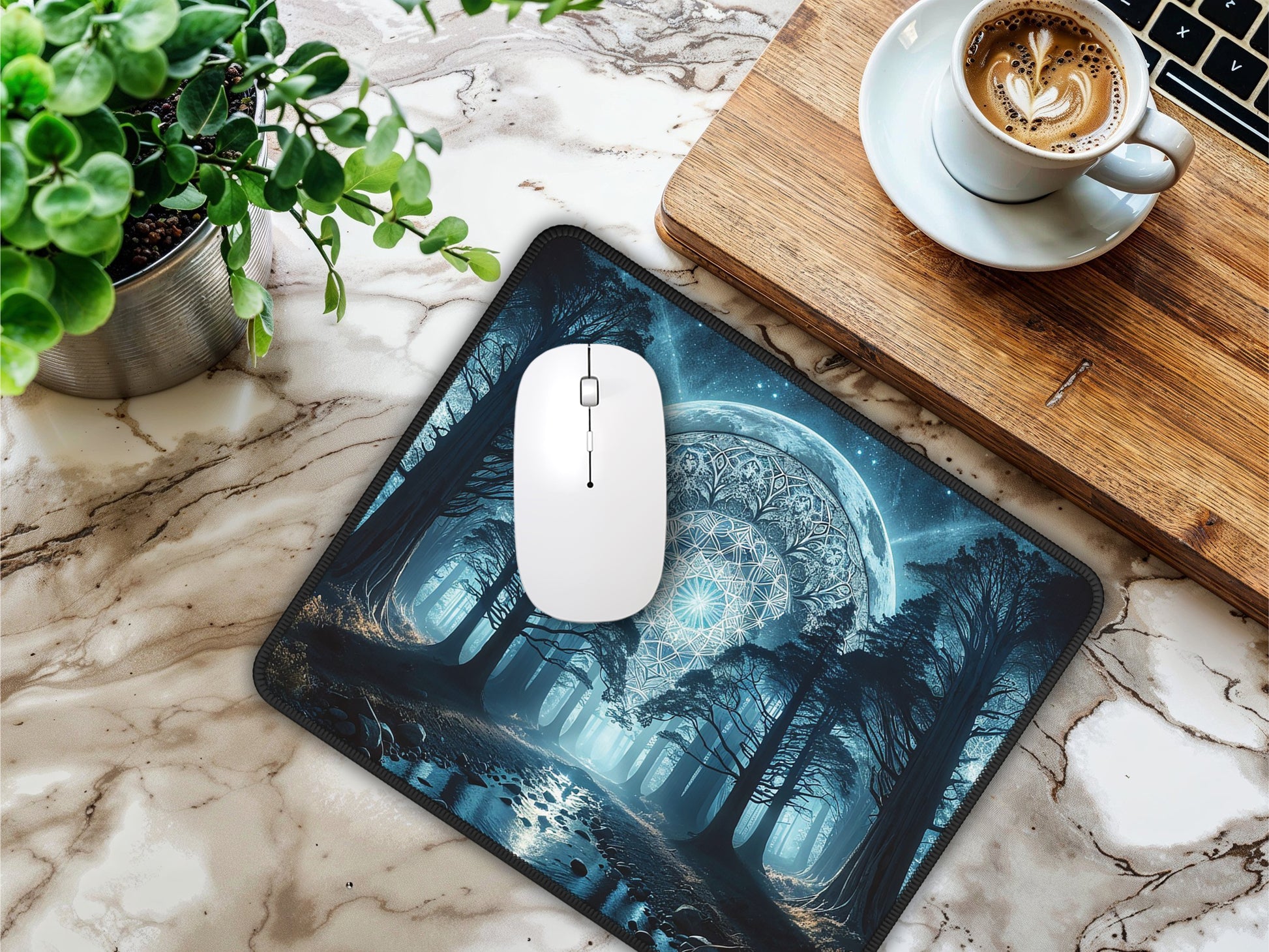 Desk setting with the moonlit forest mouse pad next to a laptop, cup of coffee, and indoor plant.