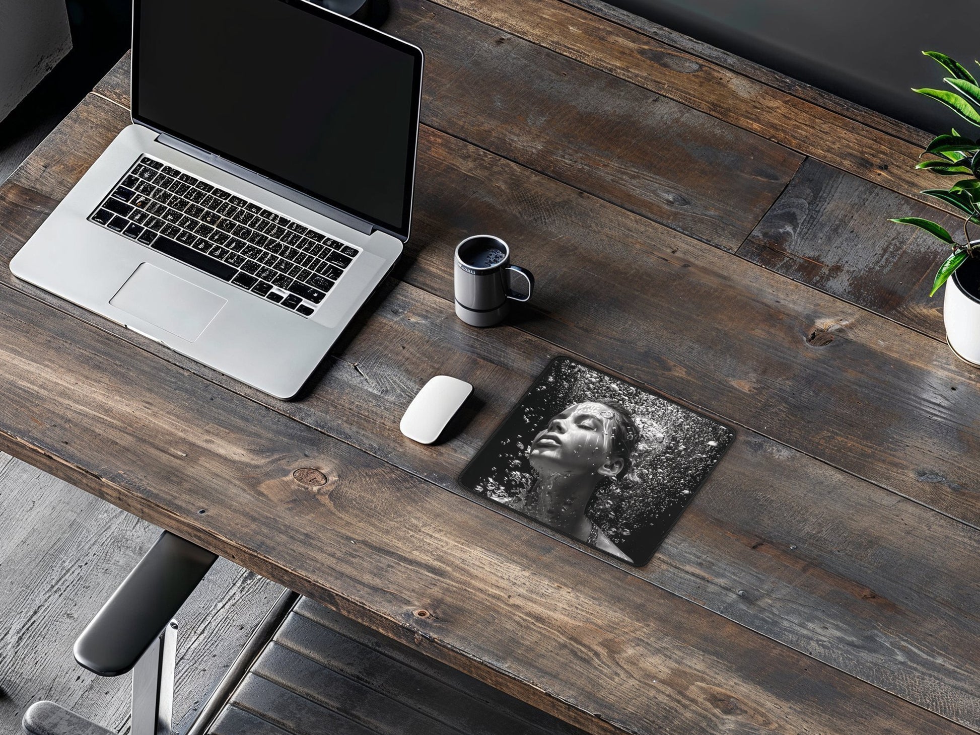 Mouse pad on a wooden desk with a laptop, coffee cup, and indoor plant, emphasizing a black and white water bubble pattern.