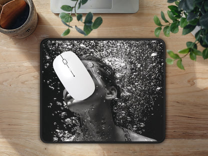 Mouse pad on a wooden table with a white mouse, displaying a black and white underwater portrait of a woman with bubbles.